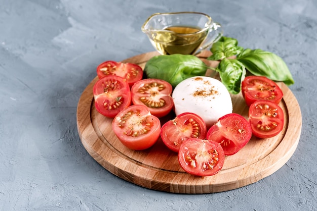 Tabla de madera con mozzarella, tomates, albahaca, cocina italiana, aceite de oliva, espacio para copiar