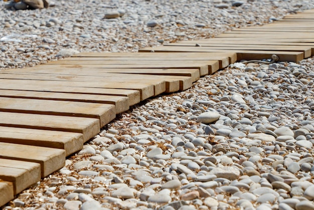 Una tabla de madera en una playa de guijarros y guijarros.