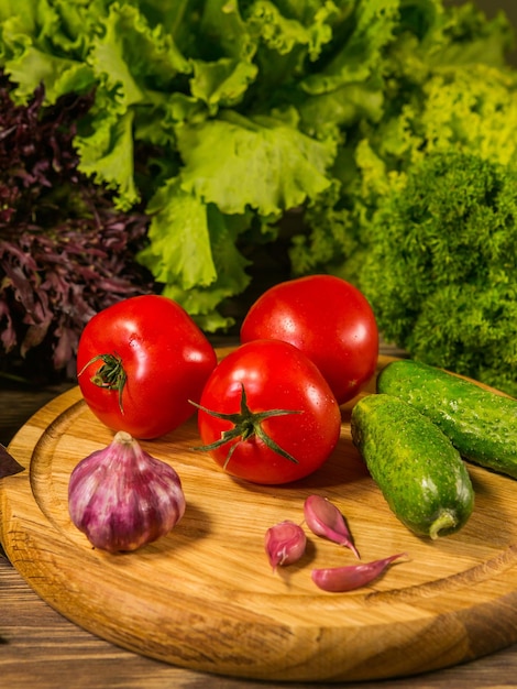 Foto una tabla de madera con tomates frescos pepinos y ajo composición con verduras frescas