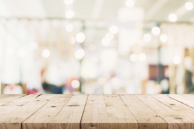 Tabla de madera vacía y fondo borroso - la tienda del bokeh del fondo de la falta de definición de la alameda de compras con el montaje de la exhibición para el producto.