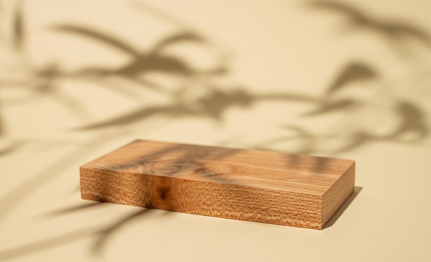 Tabla de madera vacía con sombras y hojas verdes en un fondo amarillo con sombra