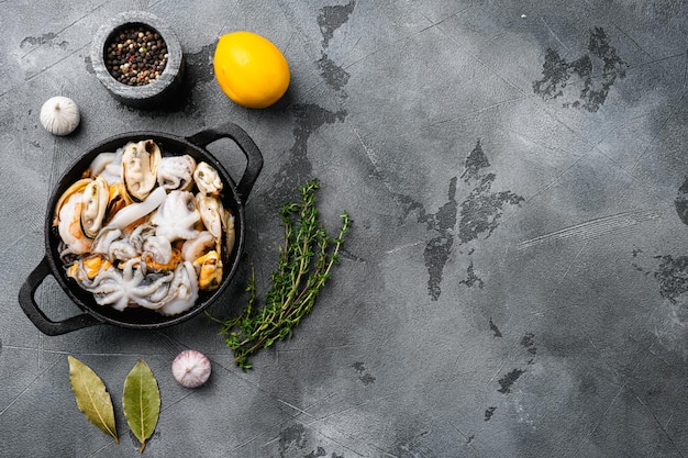 Tabla de mariscos con camarones, mejillones de calamar y conjunto de pulpo, sobre fondo de mesa de piedra gris, vista superior plana, con espacio para copiar texto