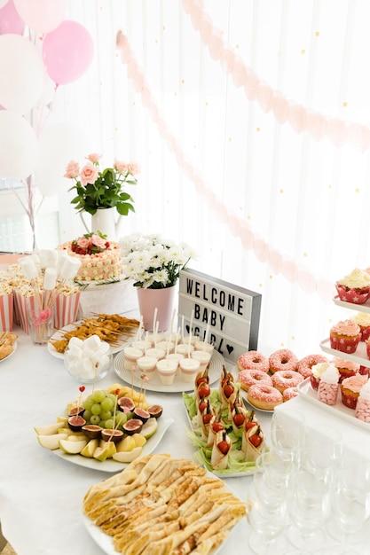 Foto tabla de pastel de ducha de bebé decoración de jardín rústico fiesta de baño de bebé para niña golosinas sabrosas en la mesa en la habitación decorada con globos