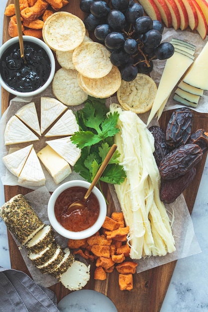 Foto tabla de quesos con frutas y galletas