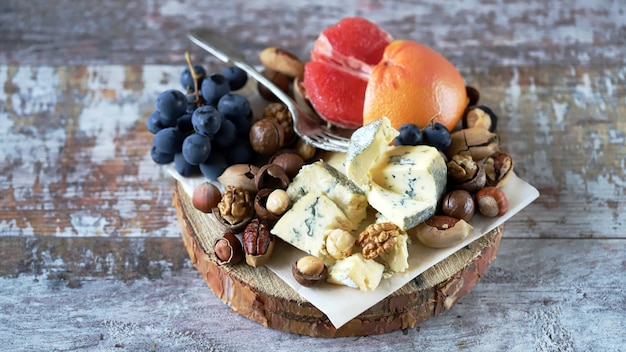 Tabla de quesos Queso con nueces pomelo y uvas en una tabla de madera Aperitivos saludables