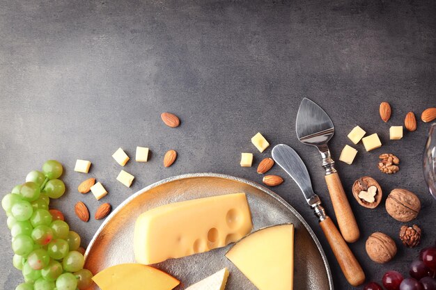 Tabla de quesos con uva y nueces en mesa gris