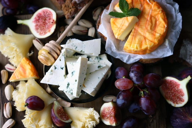 Tabla de quesos con uvas, higos, pistachos y miel. Diferentes tipos de quesos.