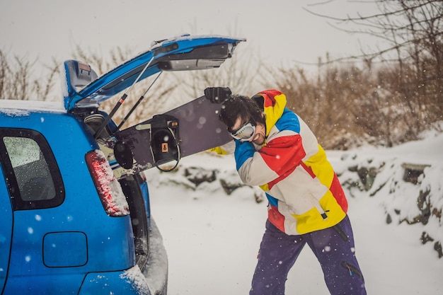 La tabla de snowboard no cabe en el automóvil Un snowboarder está tratando de meter una tabla de snowboard en un automóvil Humor divertido