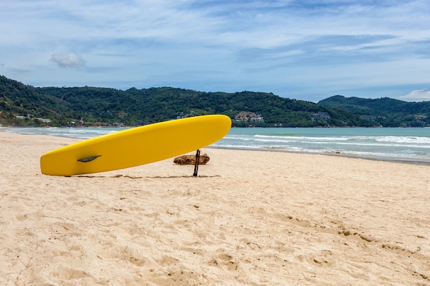 Tabla de surf amarilla en la playa con montaña en Patong Beach