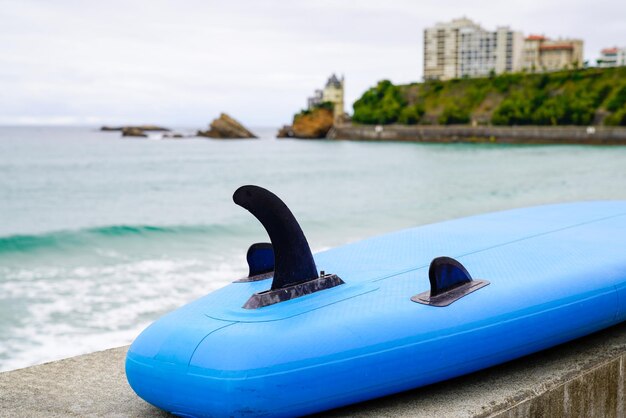 Tabla de surf azul colocada en la playa frente al mar frente al océano Atlántico en biarritz