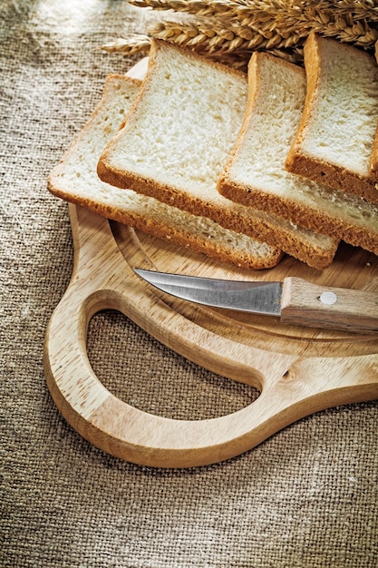 Tabla de tallar cuchillo de cocina pan en rodajas orejas de trigo sobre fondo de saqueo