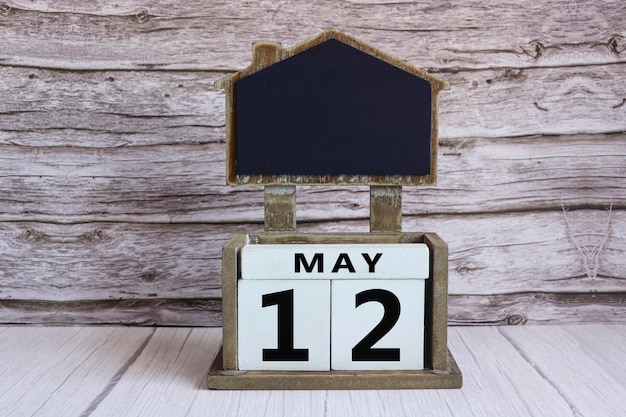 Tabla de tiza con la fecha del 12 de mayo en un bloque de cubo blanco en una mesa de madera