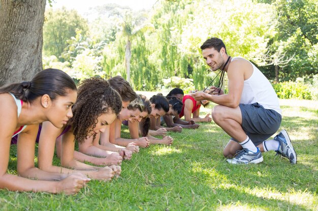 Tablaje de grupo de fitness en el parque con el entrenador