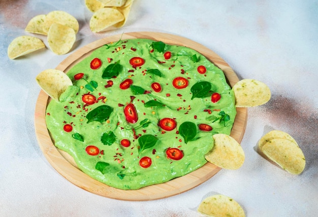 Tablero de aguacate cremoso con chiles, hierbas y nachos Enfoque selectivo con primer plano borroso y