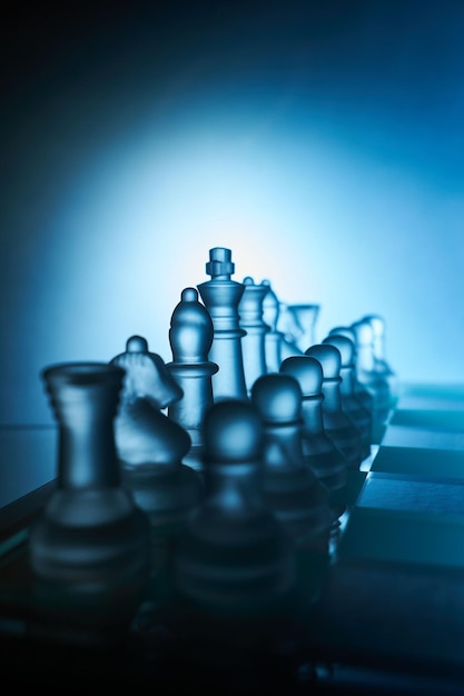 Tablero de ajedrez y figuras de ajedrez transparentes con fondo azul en primer plano.