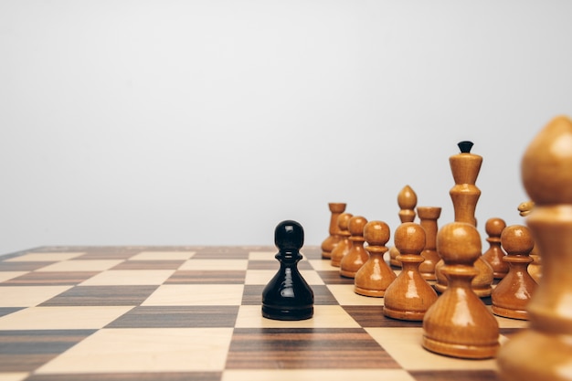 Tablero de ajedrez con figuras de madera contra la vista frontal de fondo gris