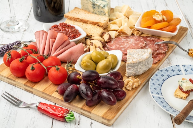 Tablero de aperitivos con queso, nueces, frutas, tostadas y charcutería sobre mesa de madera