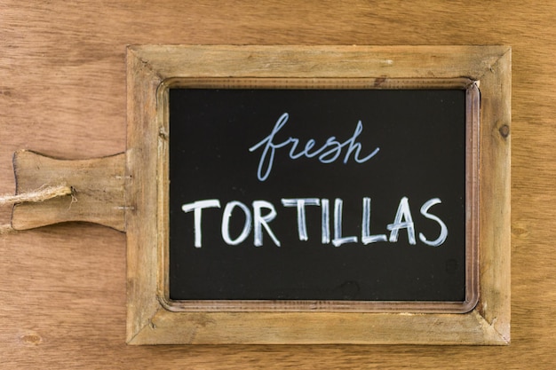 Tablero de chack con cartel de tortillas frescas.