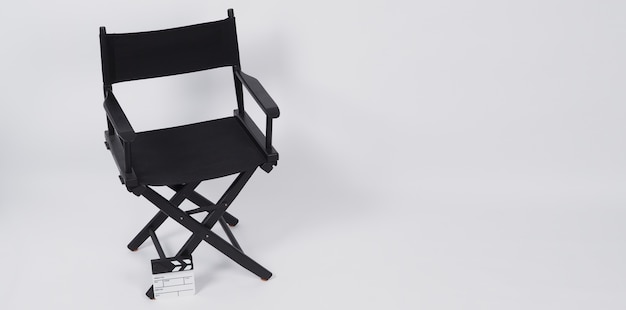 Tablero de chapaleta o pizarra de película con silla de director para uso en producción de video o industria cinematográfica y cinematográfica. Se pone sobre un fondo blanco.