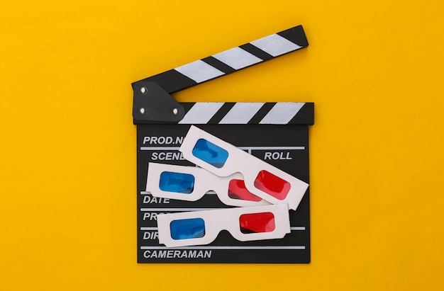 Tablero de chapaleta de película con gafas 3d retro sobre fondo amarillo. Cine, realización de películas, producción de películas, industria del entretenimiento. Vista superior