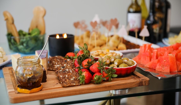 Tablero de charcutería elegantemente arreglado que muestra varias carnes, quesos, frutas y nueces.