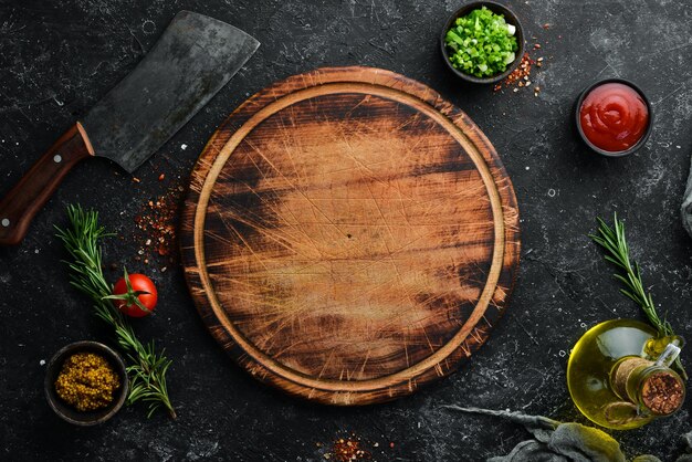 Tablero de cocina y verduras con especias sobre fondo de piedra negra Vista superior Espacio libre para el texto