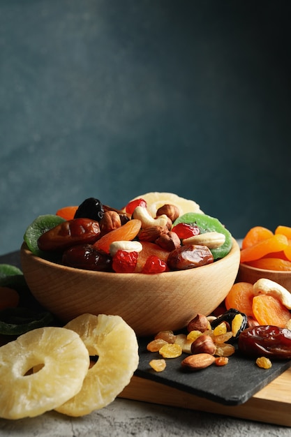 Tablero y cuencos con frutos secos y nueces en mesa gris