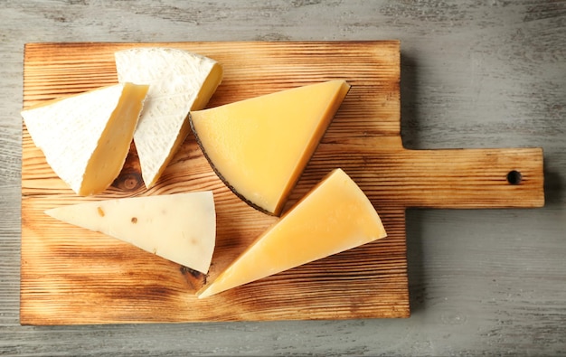 Tablero con delicioso queso en mesa de madera