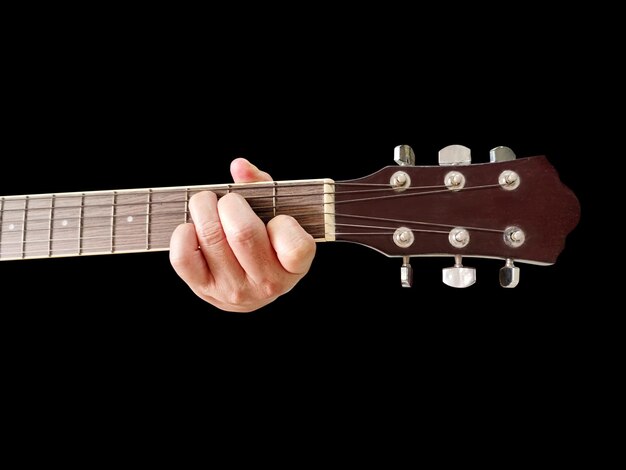 tablero de la guitarra y la mano del guitarrista sosteniendo la tablero Imagen de una tablero en un fondo negro