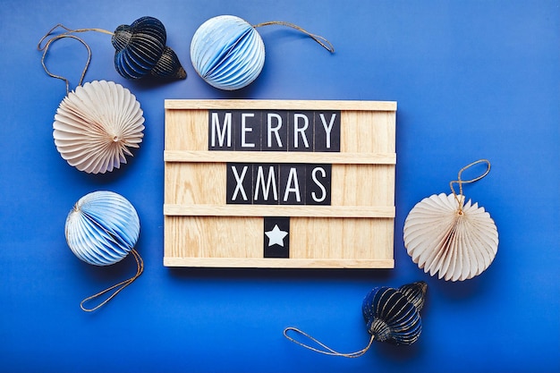 Tablero de letras con texto feliz navidad con decoración navideña sobre fondo azul flatlay