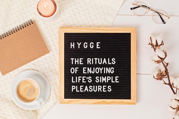 Tablero de letras con texto hygge los rituales de disfrutar de los placeres simples de la vida. Comodidad y acogedor concepto de vida lenta. Plano, vista superior