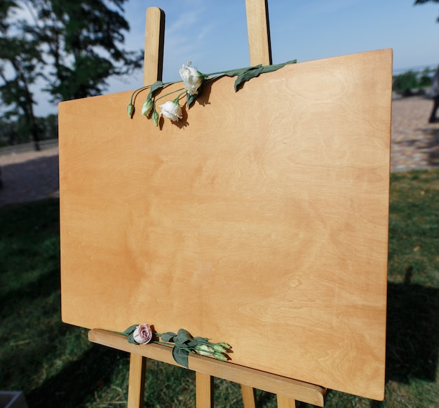 Foto tablero de madera en caballete para escribir o para dibujar con espacio de copia. elegante decoración festiva en la fiesta de bodas.