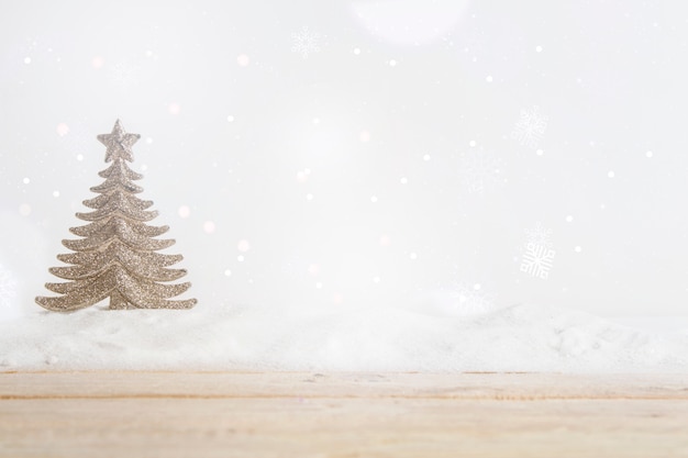 Tablero de madera cerca de árbol de navidad de juguete en montón de nieve