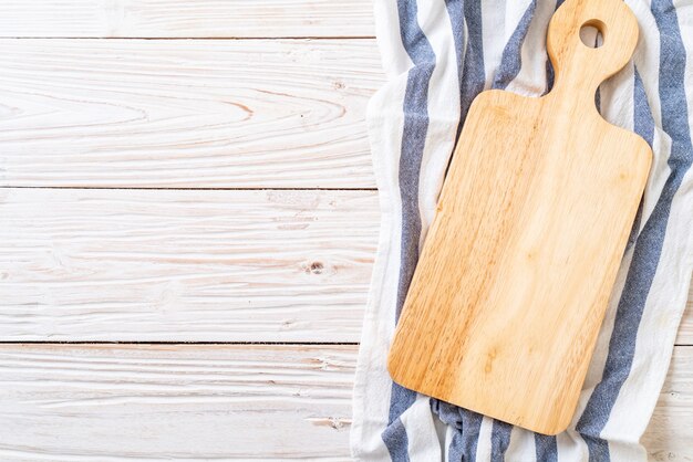 Foto tablero de madera de corte vacío con paño de cocina sobre fondo de madera, vista superior