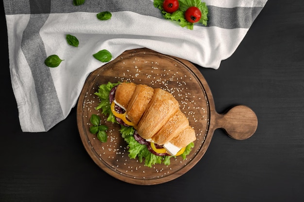 Tablero de madera con delicioso sándwich de croissant en la mesa