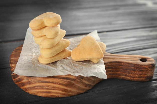 Tablero de madera con galletas de mantequilla en forma de corazón en la mesa