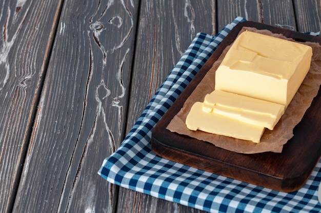 Tablero de madera con mantequilla en servilleta a cuadros azul