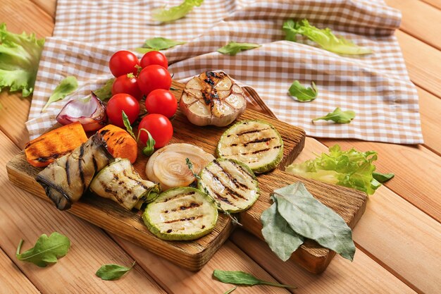 Tablero de madera con sabrosas verduras asadas en mesa