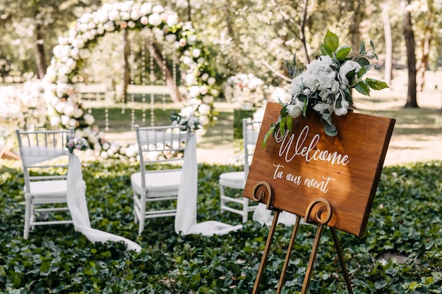 Foto tablero de madera con texto de bienvenida a nuestro evento en una boda en el pasillo