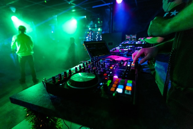 Tablero mezclador de música profesional con las manos de un DJ en una fiesta