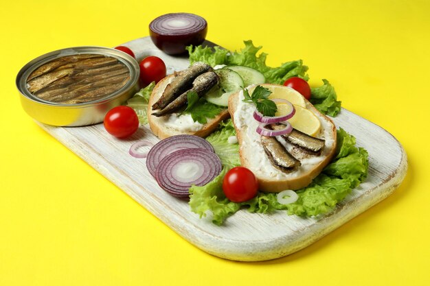 Tablero con sándwiches con espadines sobre fondo amarillo