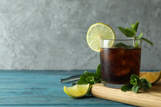 Tablero con vaso de Cuba Libre sobre mesa de madera