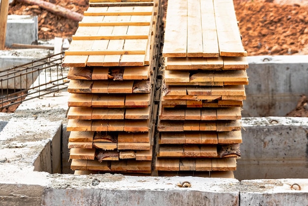 Tableros de encofrado de madera apilados en el sitio de construcción Almacenamiento de materiales de construcción en el sitio de construcción Encofrado para cimientos de tiras