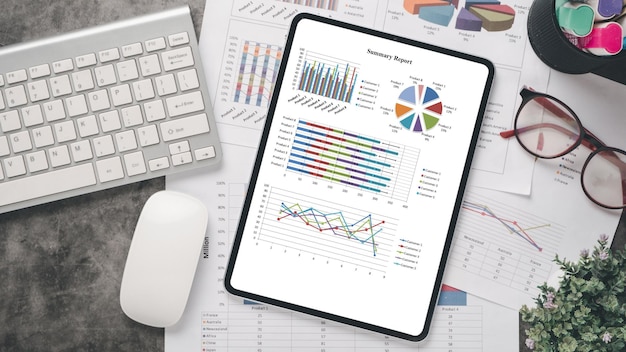 Tablet com gráficos e relatórios sobre o local de trabalho de escritório Vista superior plana layx9