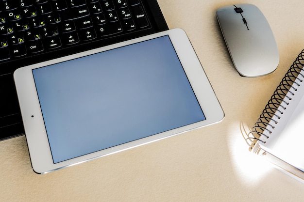 Tablet com tela em branco ao lado de um laptop em uma mesa Conceito de tecnologia e negócios