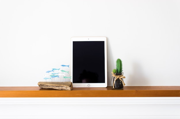 Tablet com tela em branco na madeira com cactus