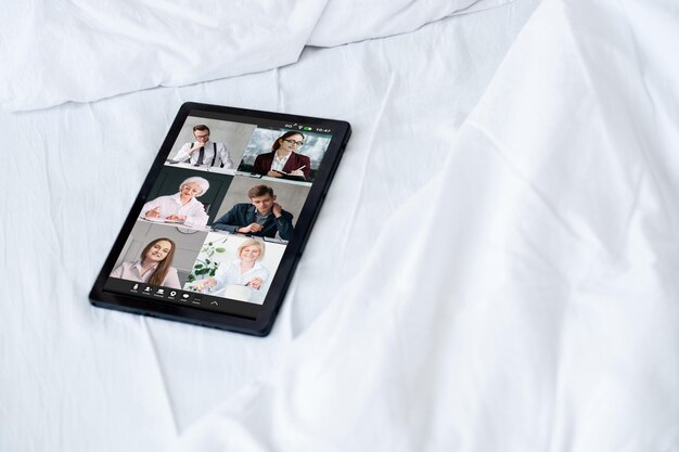 Tablet de equipe de negócios de teleconferência em casa na cama