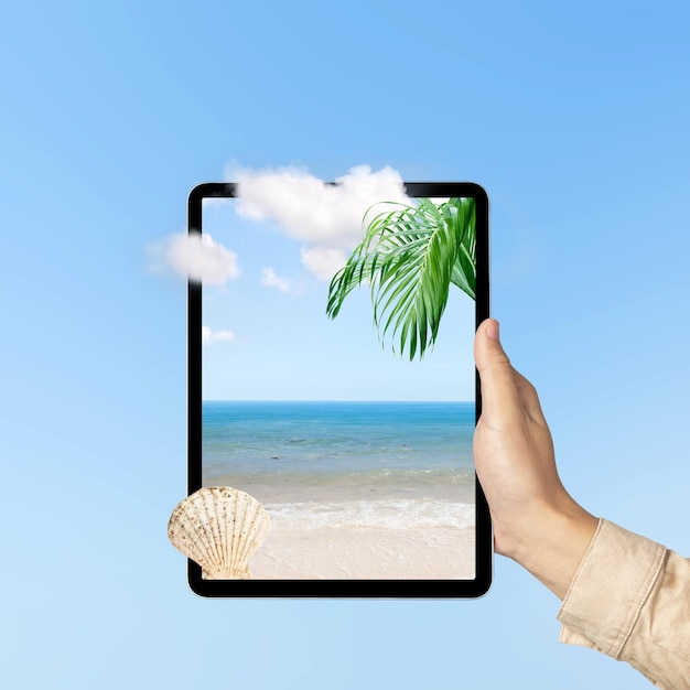 Tablet de mão humana com uma vista de tela da praia com uma vista do oceano e do céu azul