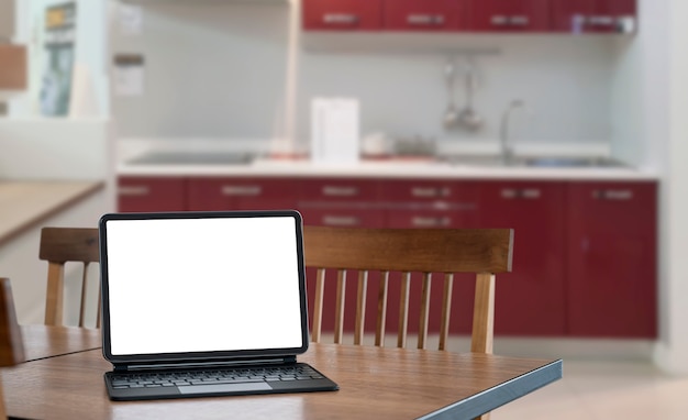 Tablet de tela em branco com teclado mágico na mesa de madeira na sala de kitcher.