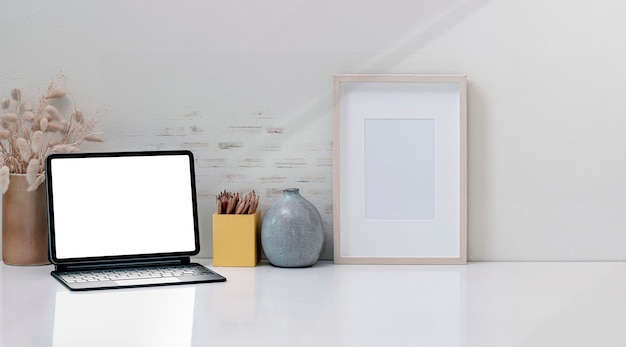 Foto tablet de tela em branco de maquete com teclado mágico na mesa superior branca.